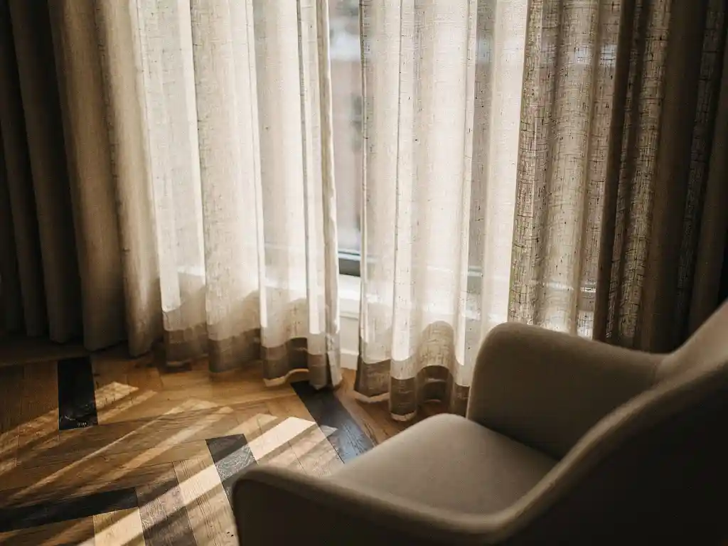 Vloerlange linnen gordijnen in ivoor en taupe tinten naast een hoog raam in een Hollands interieur met visgraat eiken vloer.
